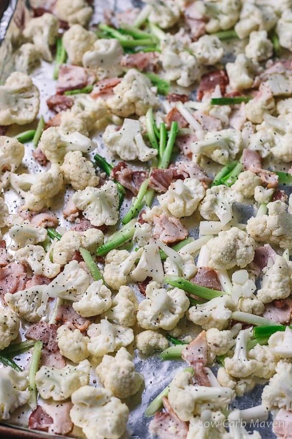 Cauliflower florets, bacon and green onions on a sheet pan. 