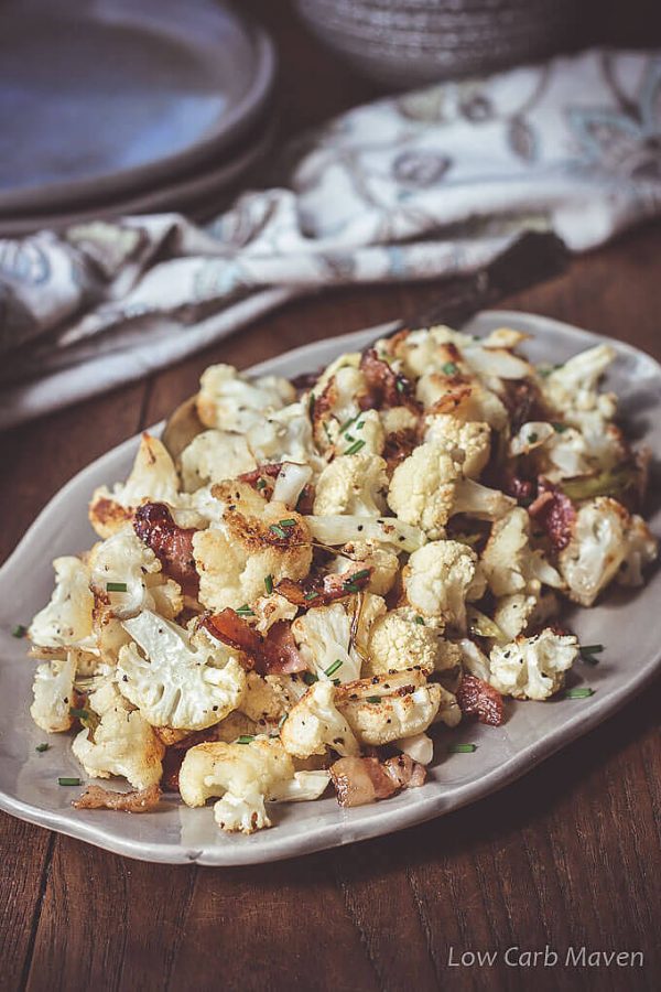 Cauliflower roasted with bacon and green onions on an oval platter. 