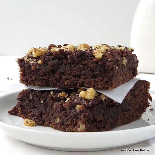 Two moist low carb brownies topped with walnuts stacked on a white plate.