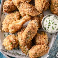 Crispy garlic Parmesan chicken wings on a platter with dipping sauce.