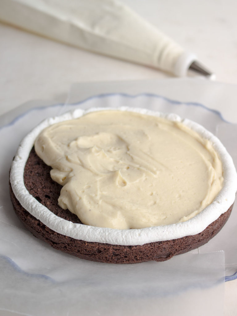 The first layer of a chocolate layer cake with piped whipped cream "dam" and vanilla pudding filling.