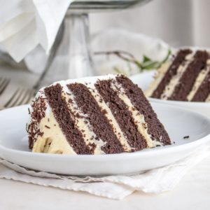 A slice of low carb chocolate layer cake filled with vanilla pudding, on a plate.