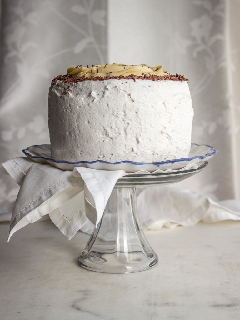 Chocolate cake with white frosting on a cake stand.