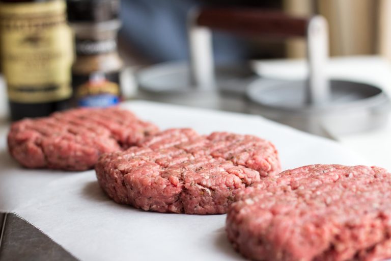 Burger patties and double burger press with steak seasoning and Worcestershire sauce.