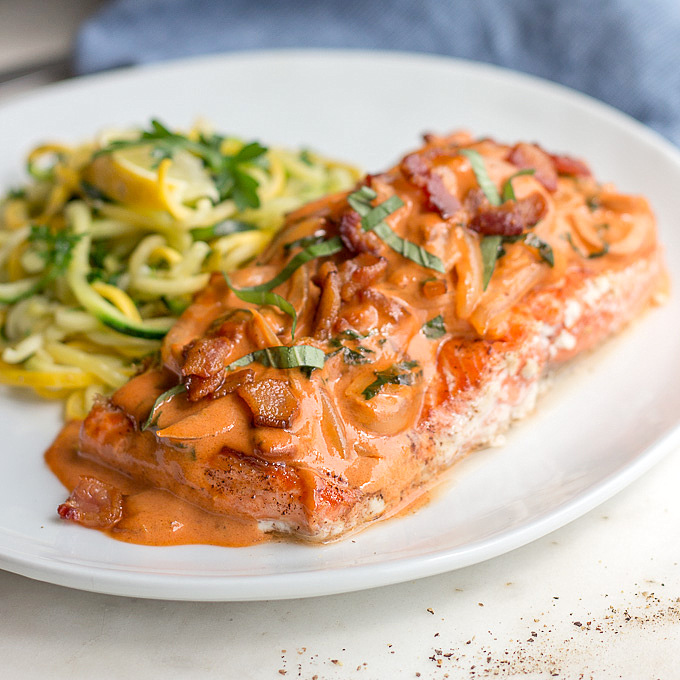 Salmon with Bacon Tomato Cream Sauce: A sexy dish with a luxurious tomato vodka cream sauce featuring bacon! Ready in 20 minutes.