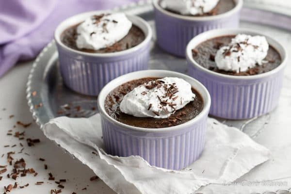 Low Carb Chocolate Truffle Creme Brulee with whipped cream in ramekins on round vintage tray.