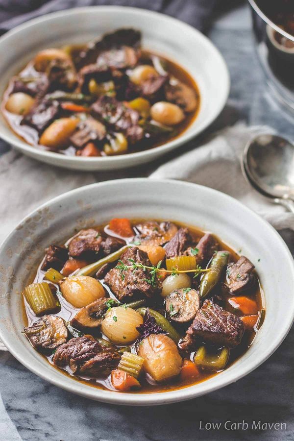 Keto beef stew with chunks of beef and and vegetables in a bowl with napkin and spoon to the side.