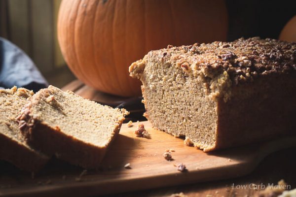 Sliced loaf of pumpkin bread on a cutting board with a pumpkin.