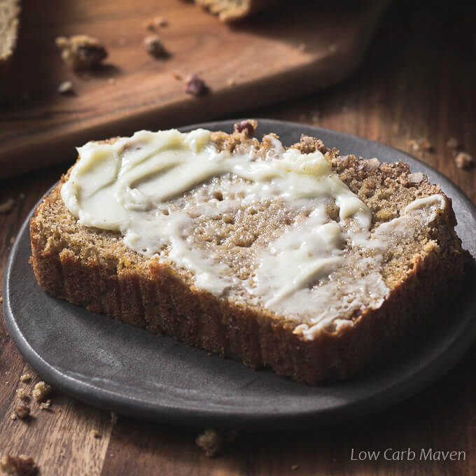 A sliced piece of gluten free pumpkin bread with butter on a plate.