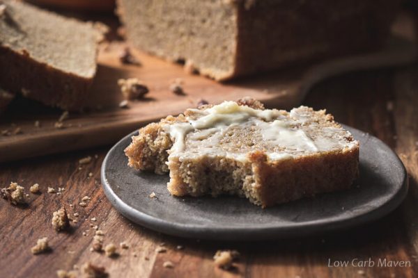 A piece of gluten free pumpkin bread with butter on a plate.