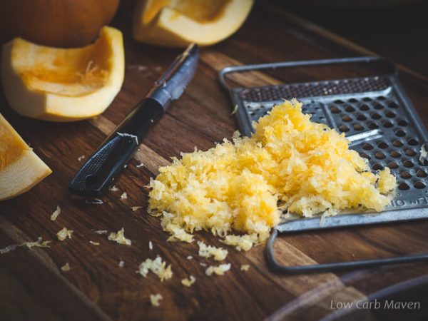 Fresh grated pumpkin with grater, peeler and cut and whole pumpkins.