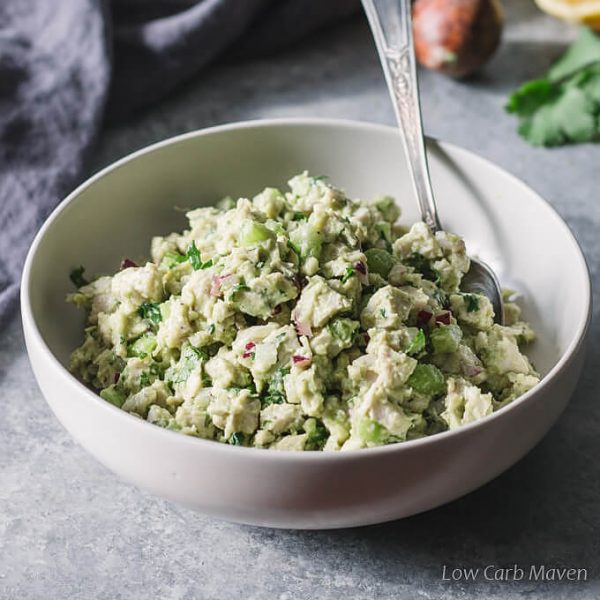 Avocado chicken salad in a bowl with spoon made from poached chicken.