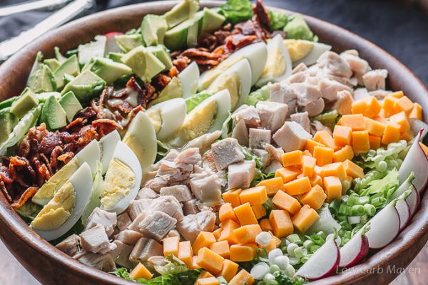 Insalata Cobb di pollo con condimenti in un'insalatiera di legno.