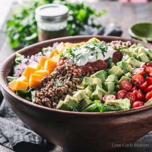 Healthy low carb taco salad with ground beef, salsa and sour cream in a wooden bowl.