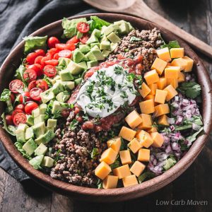 Gezonde low carb taco salade met gemalen rundvlees, salsa en zure room in een houten kom.