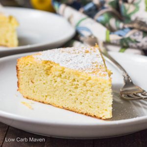 Slice of lemon ricotta cake with powdered sugar on a white plate with fork.