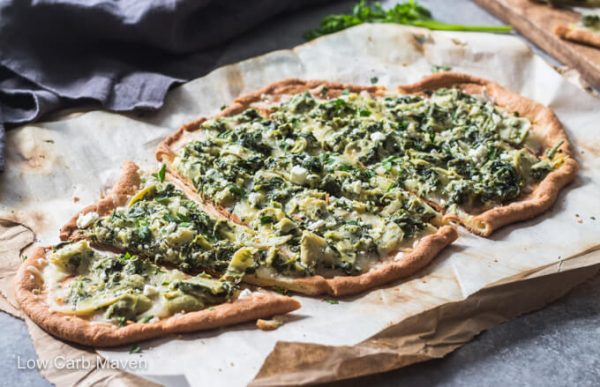 Slices of spinach artichoke pizza on cutting board.