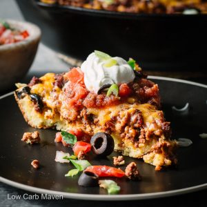 A slice of taco pie (taco bake) on a plate with Mexican seasoned ground beef baked into a cornbread crust.