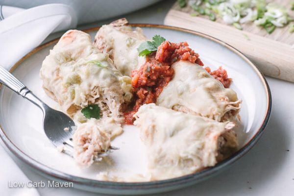 White chicken enchiladas with salsa and cilantro on a plate with fork.