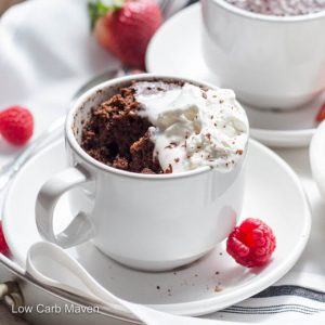 Keto chocolate cake in a cup with melted chocolate, whipped cream, and fresh raspberries and strawberries.