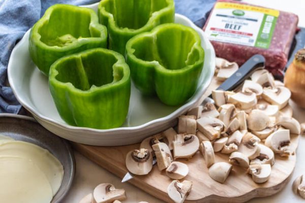 Ingredients for Philly cheesesteak stuffed peppers: green bell peppers, mushrooms, onion, ground beef and Provolone cheese.