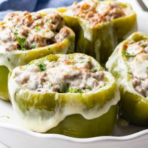 Philly cheesesteak stuffed peppers with ground beef, mushrooms and provolone cheese in a baking dish.