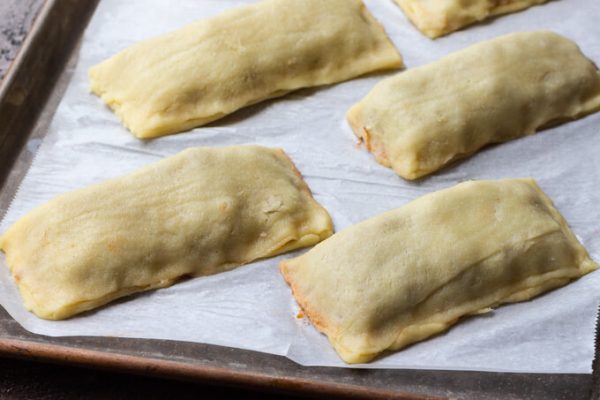 Homemade hot pockets with sloppy Joe filling on a sheet pan before baking.