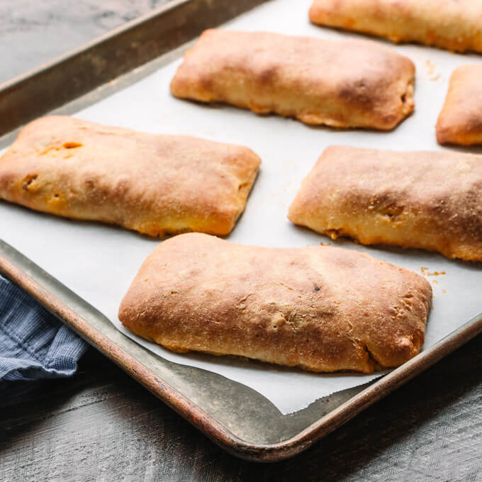 Homemade baked sloppy joe hot pockets on a sheet pan.