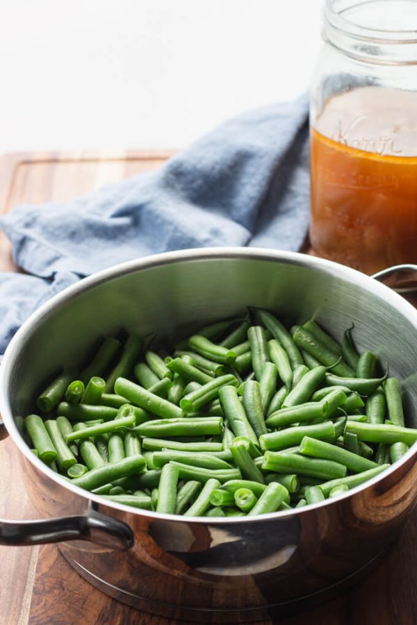 Cut green beans in a pot with ham stock in a jar. 