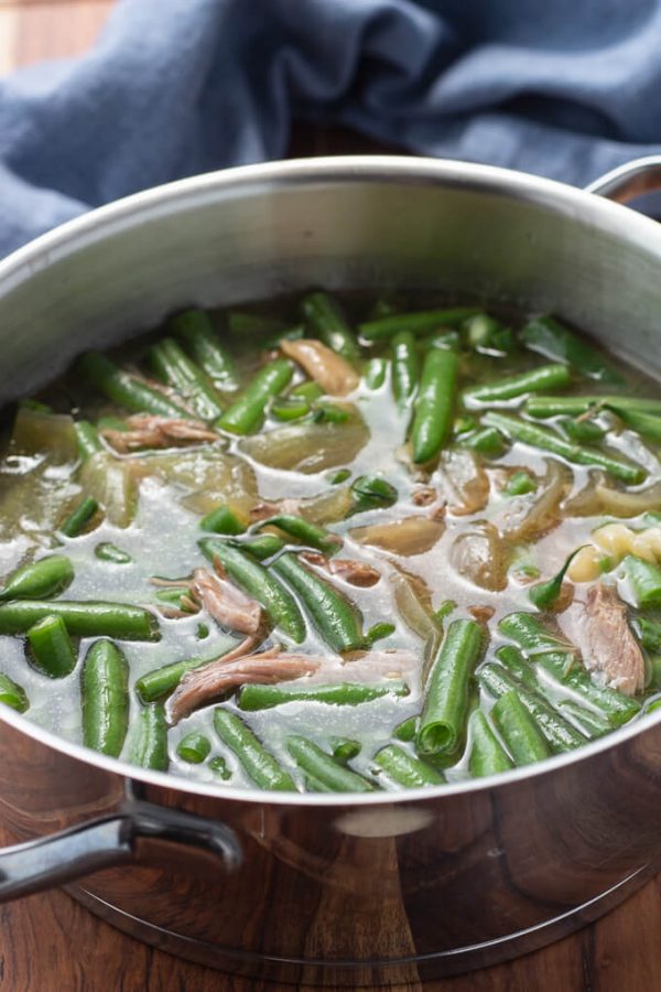 Fresh cut green beans with pork and broth in a pot. 