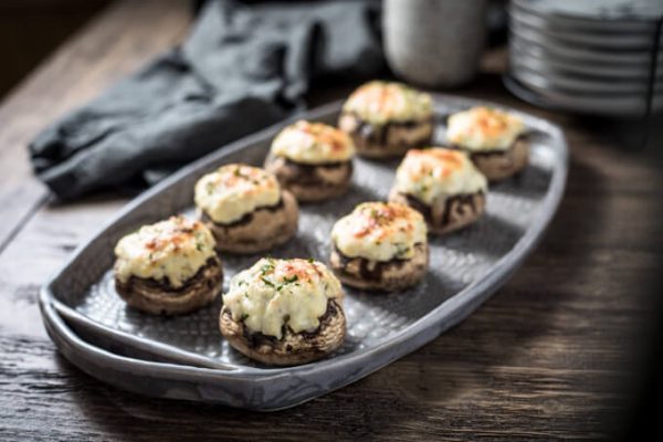 Creamy crab stuffed mushrooms with cream cheese on a platter. 