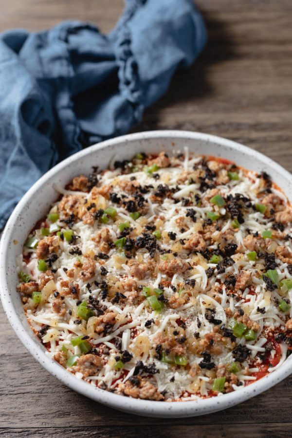 Pizza dip ingredients layered in a baking dish.