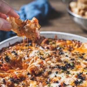 Pizza dip con crema di formaggio, salsiccia, peperone, olive nere e formaggio.