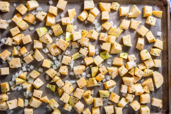 Cubed rutabaga and onions on a sheet pan.