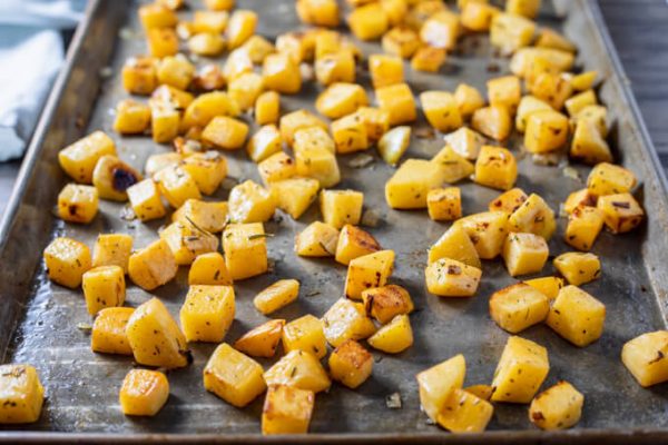 Roasted rutabaga cubes and onion on a sheet pan.