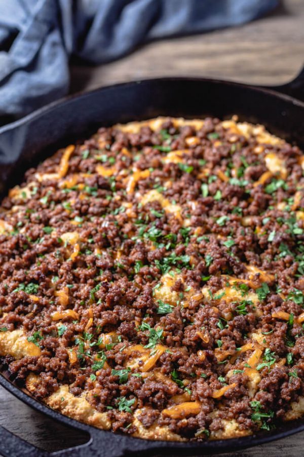 Sloppy Joe casserole with cheese in a cast iron skillet.