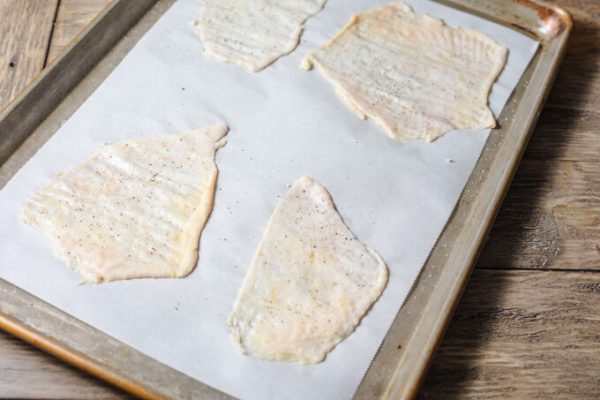 Raw chicken skin on parchment ready for baking into chips.