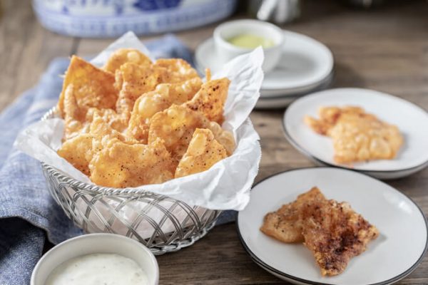 Crispy chicken skin chips or cracklings in a paper lined basket with dip.