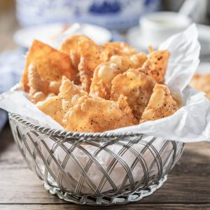 Crispy chicken skin chips in a paper lined basket.