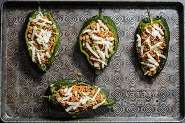 Poblano peppers stuffed with ground beef on a sheet pan before baking.