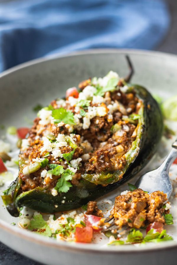 Stuffed poblano peppers with cheese and cilantro on a plate with fork.