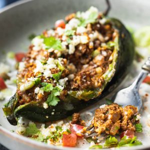 Ground beef stuffed poblano peppers with cheese on a plate with fork.