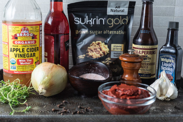 Ingredients for keto BBQ sauce: vinegar, onion, garlic, thyme, low carb sweetener, Worcestershire sauce, liquid smoke, black pepper, tomato paste and clove.