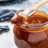 Homemade tomato based BBQ sauce in a jar with basting brush