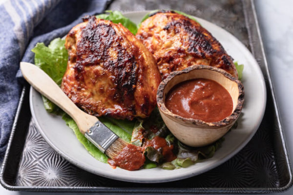 Grilled BBQ chicken breasts with individual serving of low carb bbq sauce on a plate