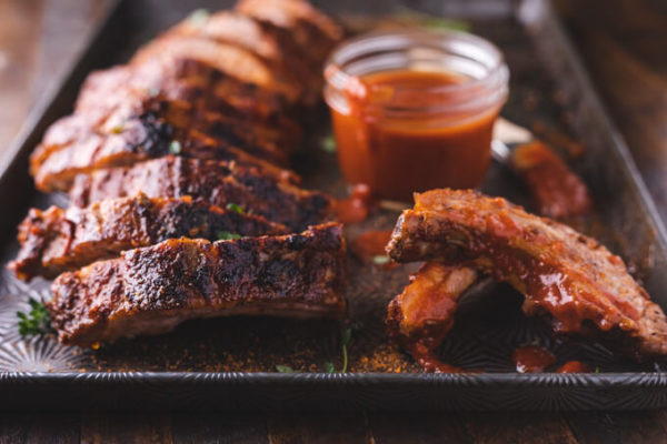 Baked and sliced pork ribs slathered with keto bbq sauce on a sheet pan