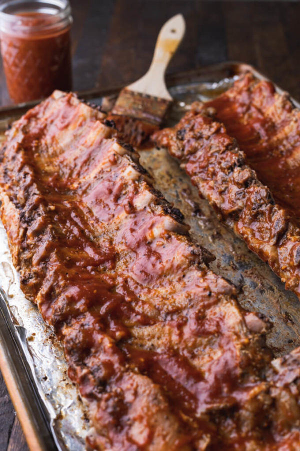 Baby back rib racks slathered in bbq sauce ready for the oven broiler