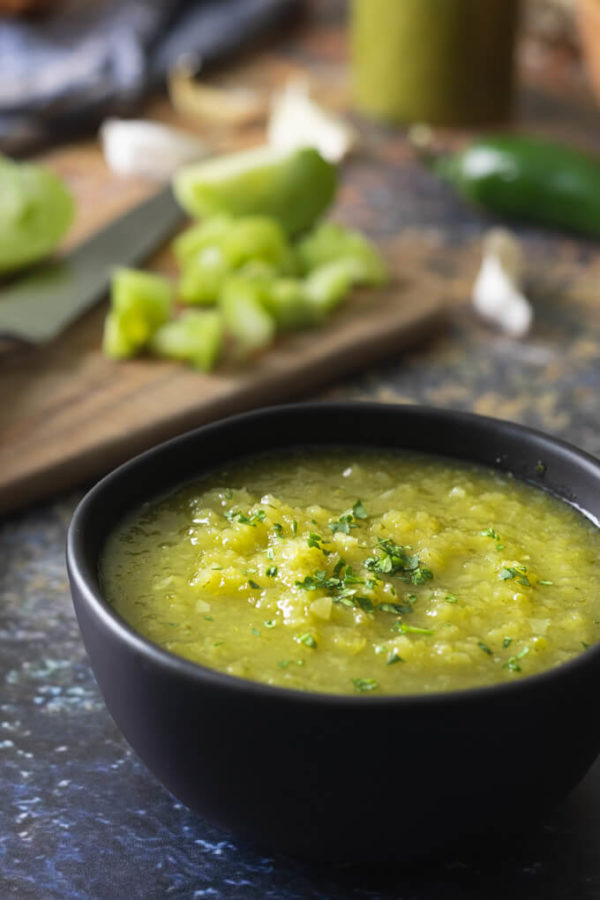 Green tomato salsa verde in a bowl with jalapenos and cilantro