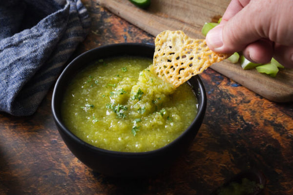 Cheese chip dipped into green tomato salsa verde