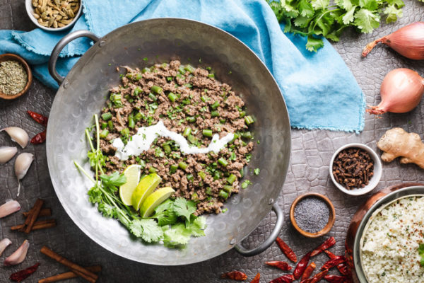 Keto green bean beef keema with yogurt, cilantro and limes in a wok with spices and red peppers